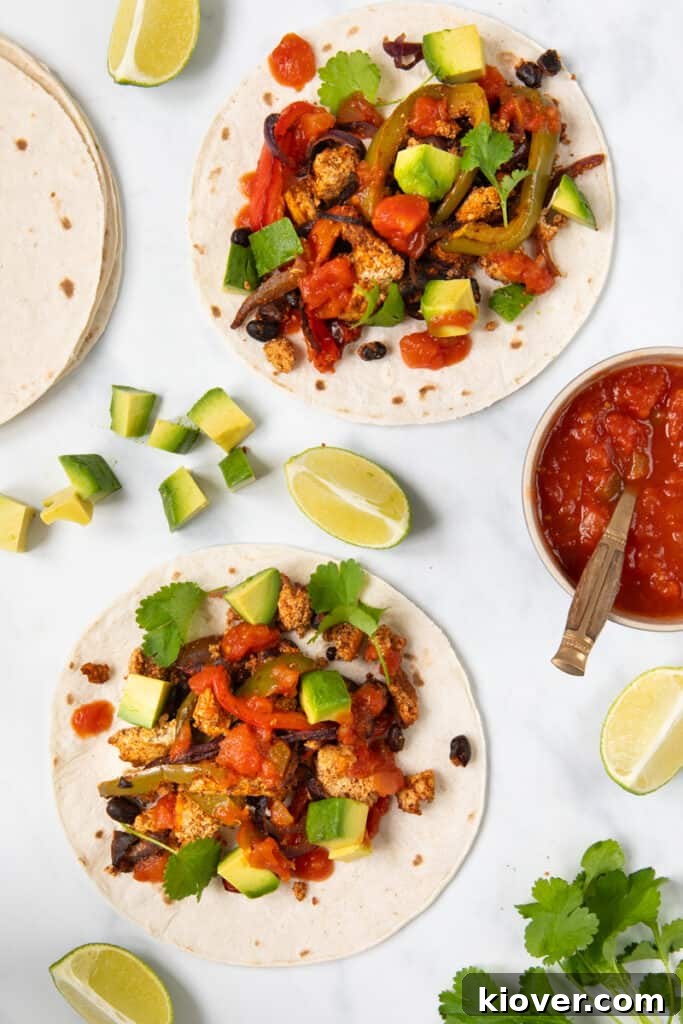 These homemade tofu fajitas are served inside gluten-free tortillas, generously topped with fresh salsa, vibrant cilantro, and creamy avocados, showcasing a perfect, healthy meal.