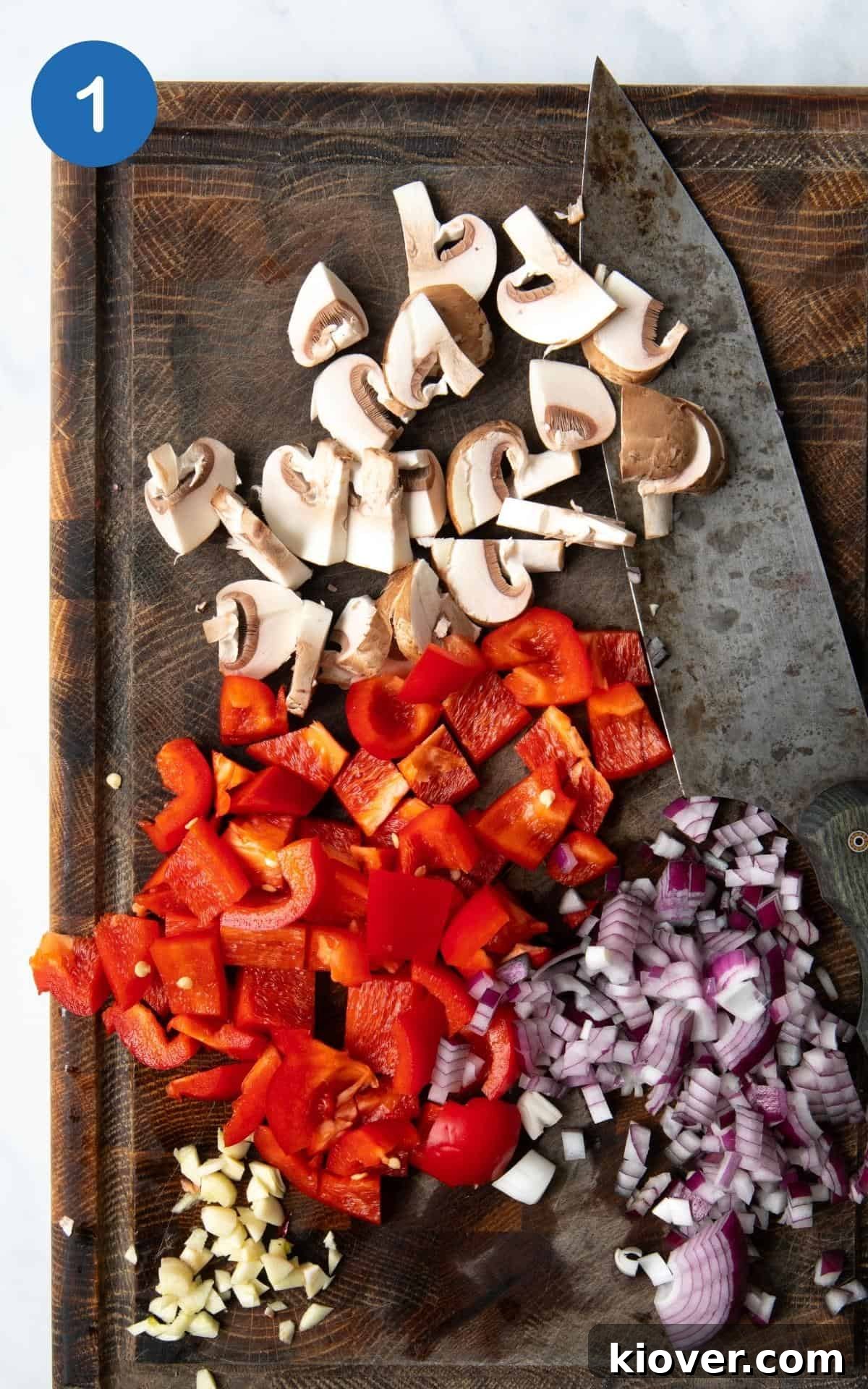 Zesty Black Bean Melts 4 Diced red onion, minced garlic, sliced chestnut mushrooms, and chopped red bell pepper neatly arranged on a chopping board, ready for cooking.