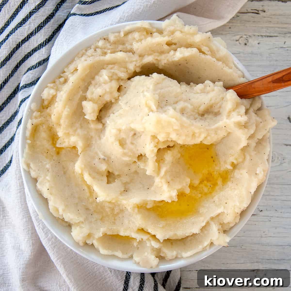 Large bowl of fluffy mashed potatoes with melted butter on top, ready to be served.