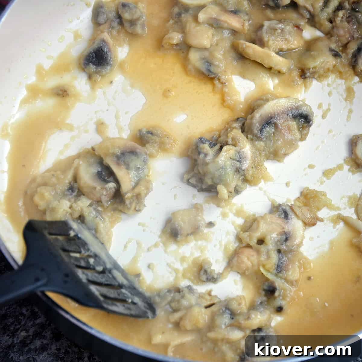 Making Mushroom Gravy A spatula in a saute pan with flour, beef broth, and mushrooms, making the gravy.