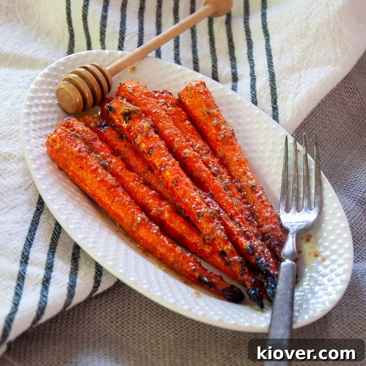 Grilled Carrots Grilled Carrots on a white plate with a fork and honey spoon.