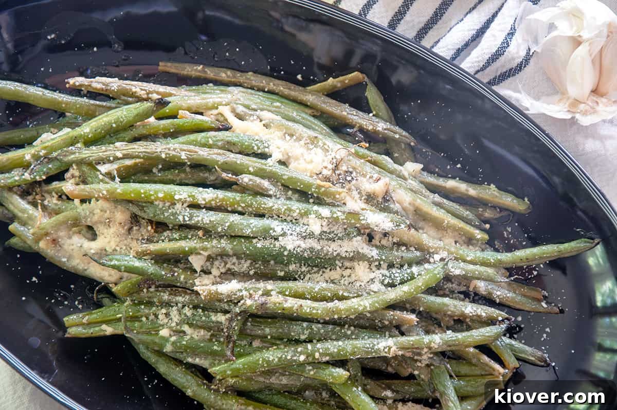 Grilled green beans arranged on a plate, topped with melted Parmesan cheese and a hint of lemon zest.