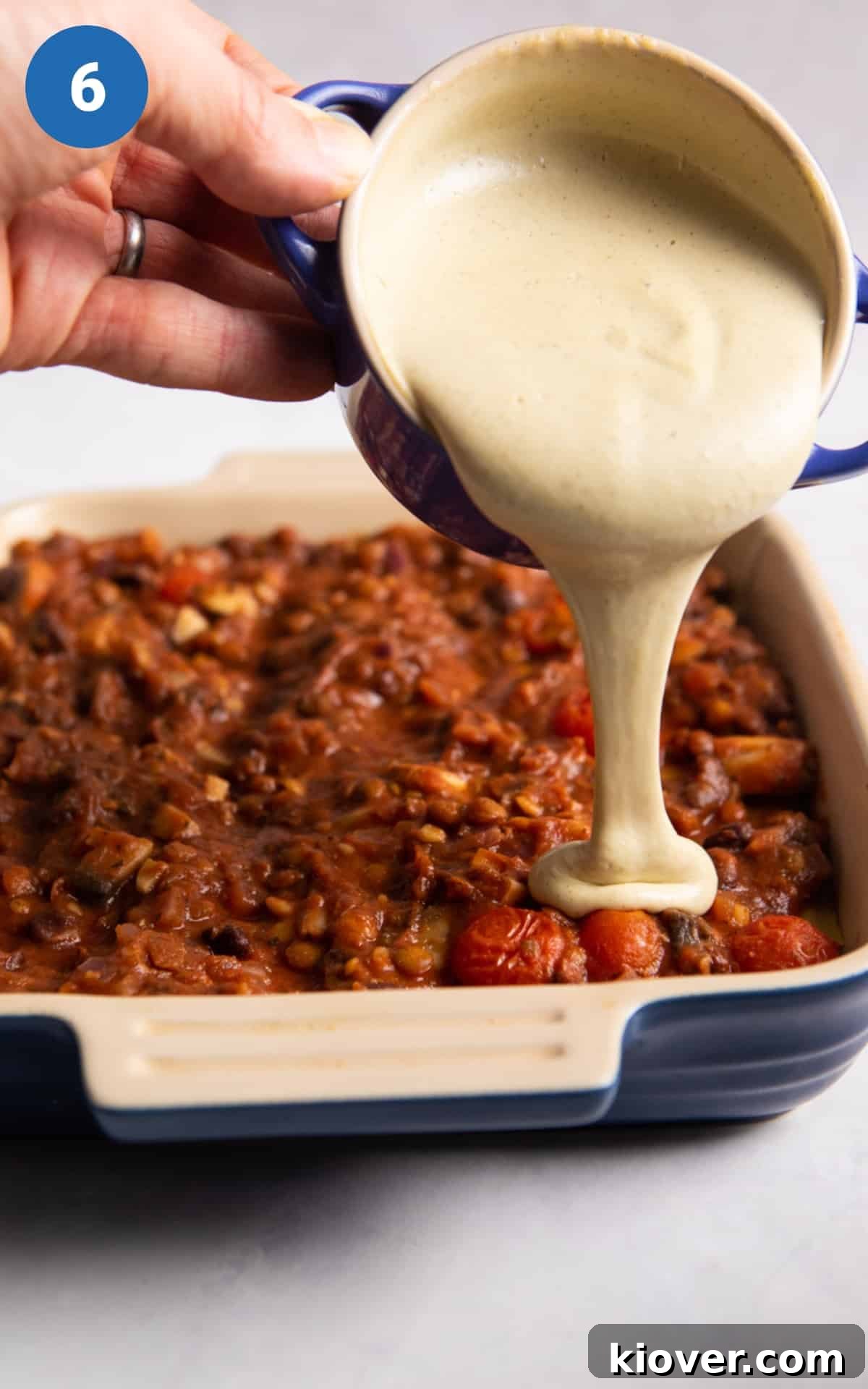 Plant-Based Lasagne Perfection 9 Thick, creamy vegan béchamel sauce being generously poured over a layer of lasagne, ensuring every part is covered for a rich flavor.