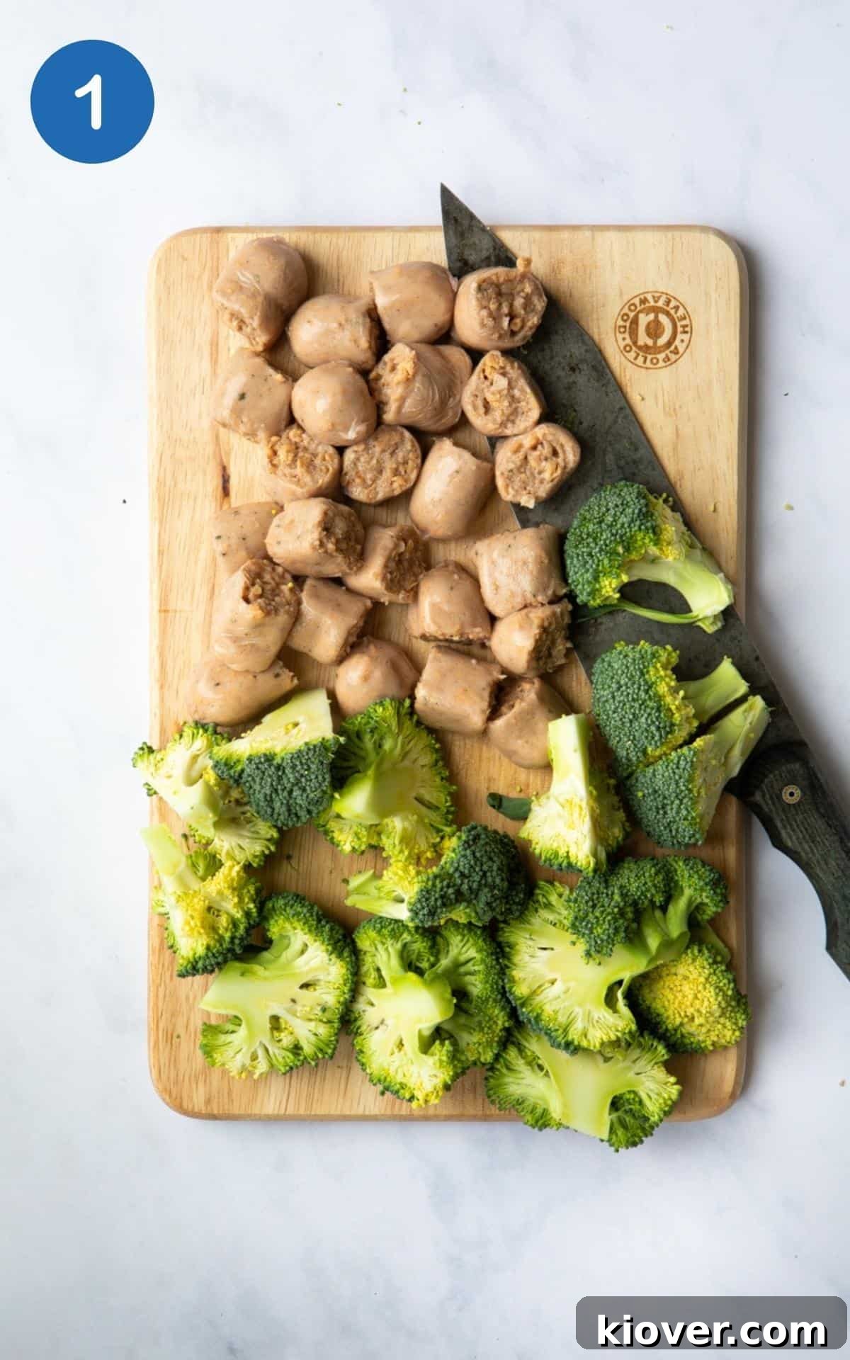 Savory Sausage Pesto Gnocchi 4 Chopped broccoli and sausages on a wooden chopping board with a knife, displayed on a white marble background.