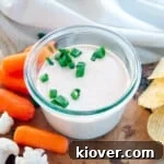 A bowl of creamy sour cream dip surrounded by colorful cauliflower, crisp carrots, and crunchy potato chips, ready for dipping.