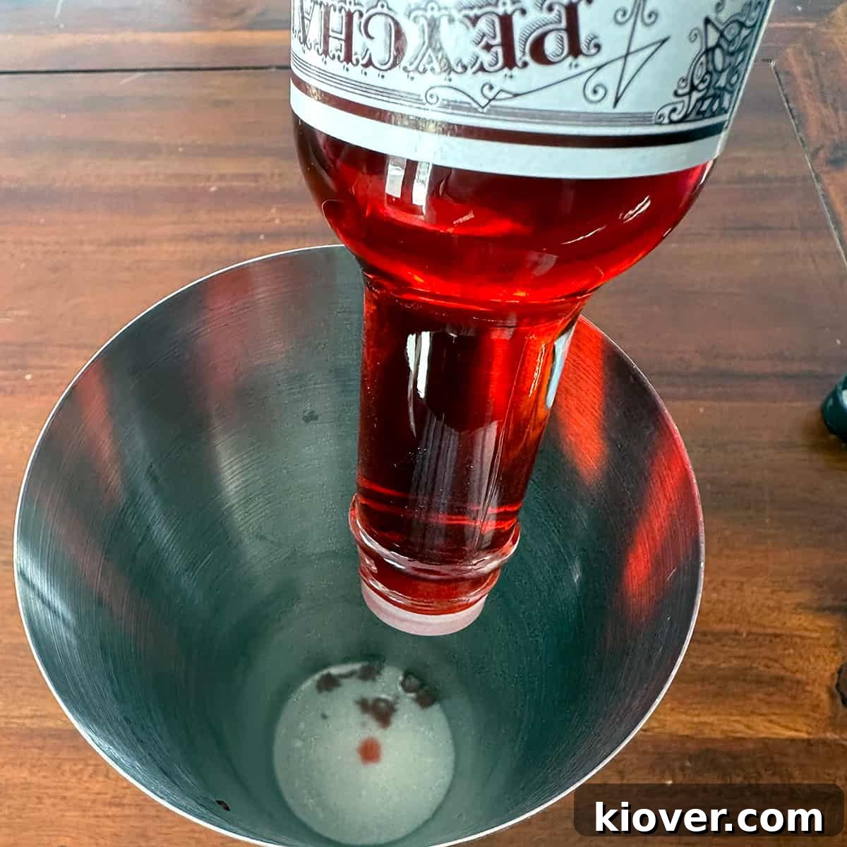 Peychaud's Bitters being shaken into a cocktail shaker with some sugar.