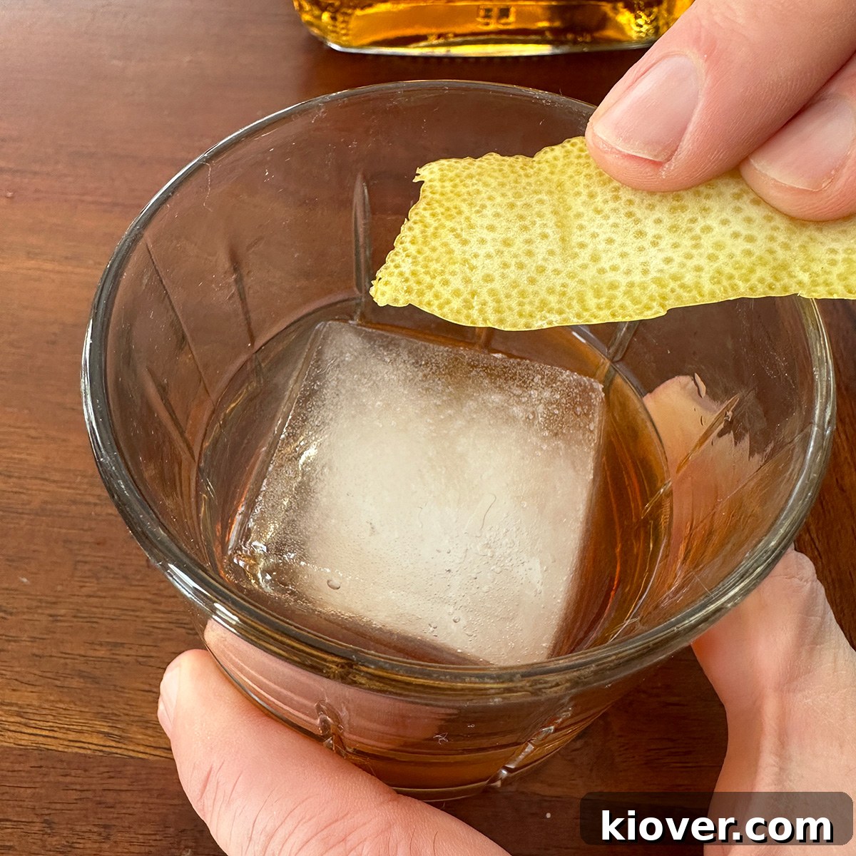 Rubbing a lemon peel along the rim of a Sazerac glass.