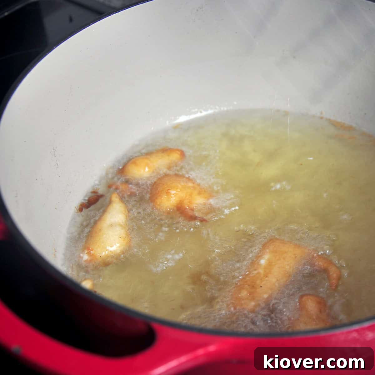 Cheese curds frying to a golden brown in a Dutch oven with hot oil.