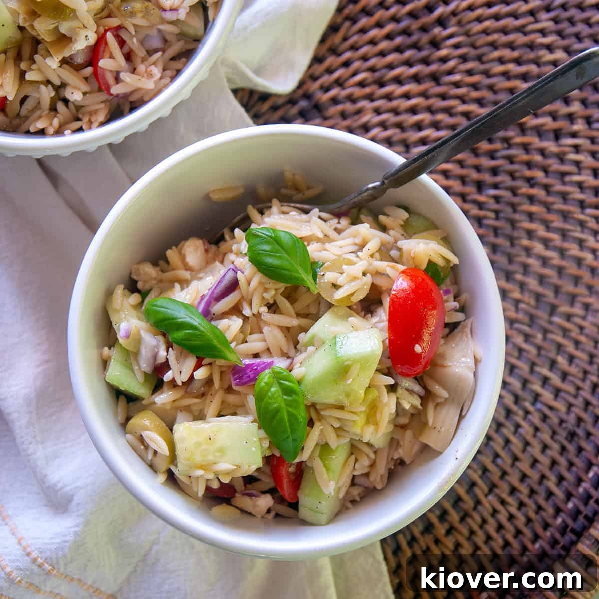 Mediterranean Orzo Salad Recipe Fresh orzo salad in a white bowl, garnished with herbs.