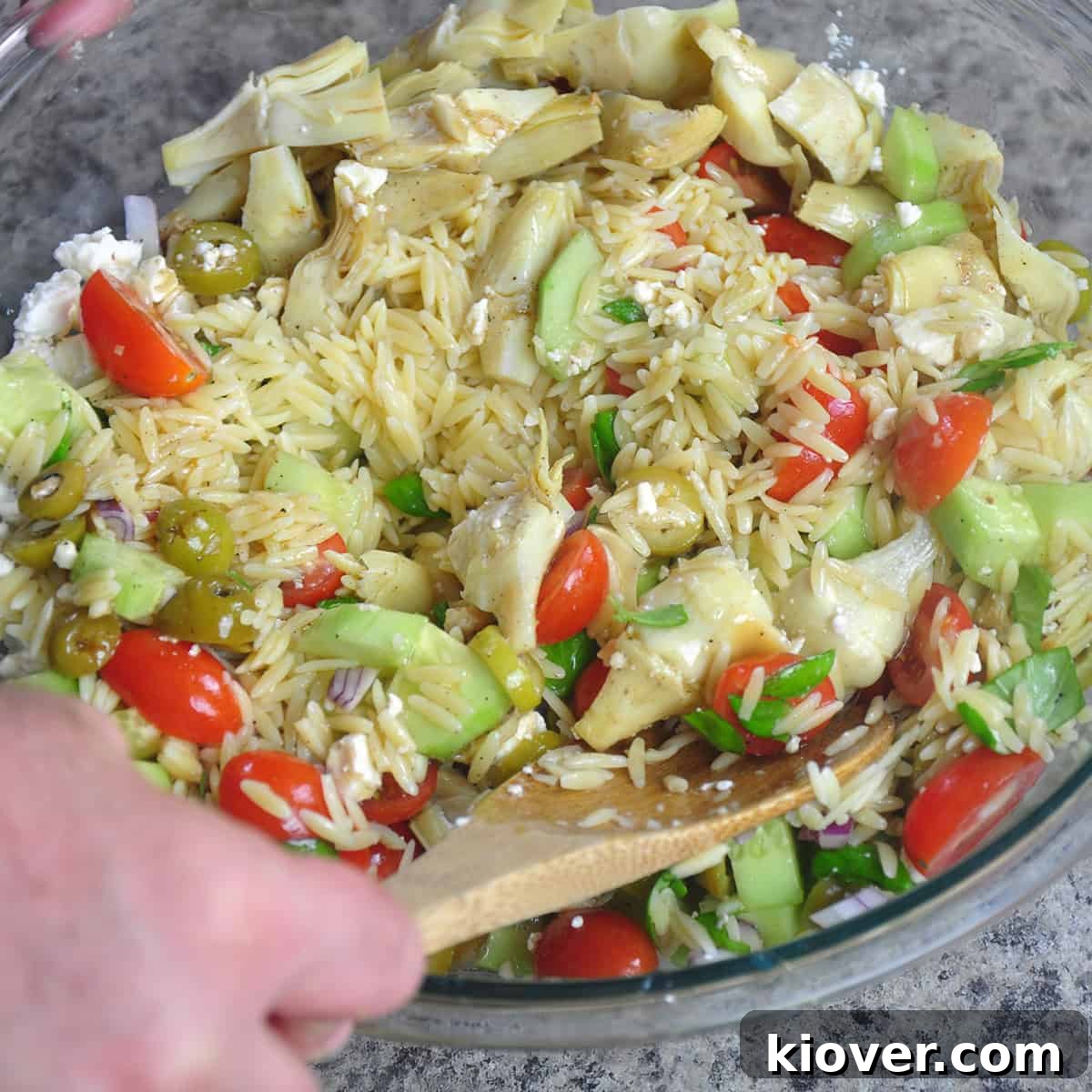 Mixing Orzo Salad Tossing the Mediterranean orzo salad ingredients together.