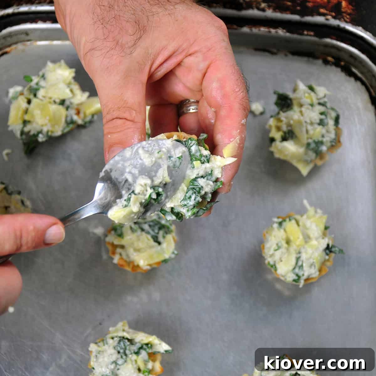 Filling Phyllo Cups A close-up shot of a spoon expertly scooping the savory artichoke dip filling into a delicate phyllo cup.