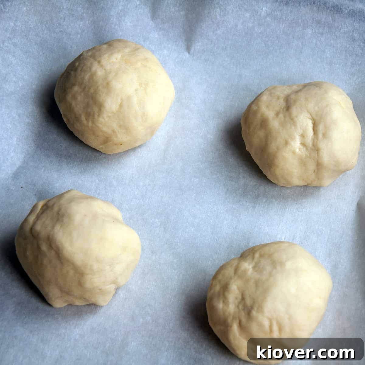 Four dough balls on a piece of parchment paper.