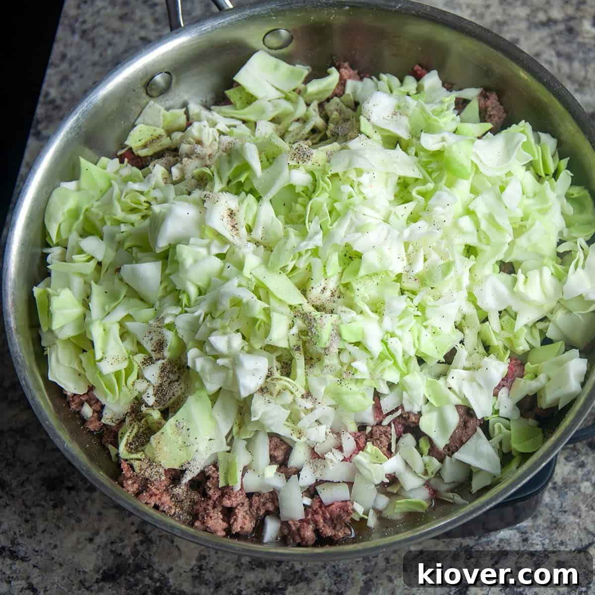 Frying pan with cabbage, burger, onion, garlic, and seasonings showing.