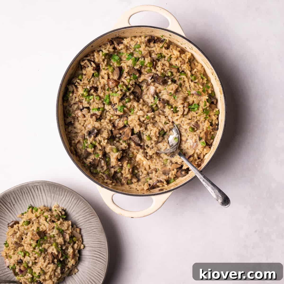 Creamy Vegan Mushroom Risotto served on a white plate with fresh herbs, showcasing its rich texture.