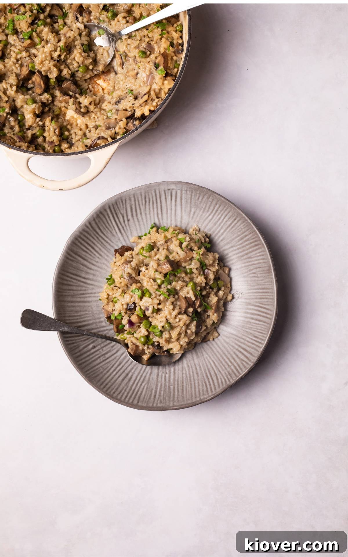 A close-up of Vegan Mushroom Risotto on a rustic grey plate, garnished with fresh parsley.