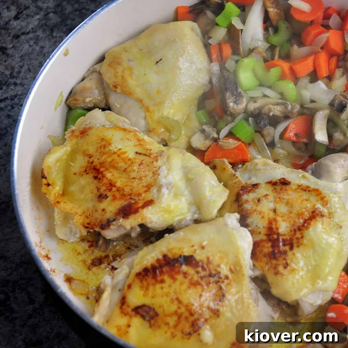 Browning Chicken Chicken browning lightly in a sauce pan alongside sautéed vegetables.