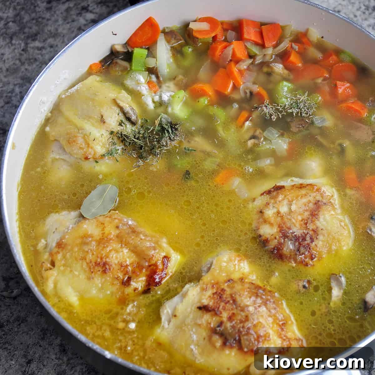 Add Stock and Herbs Chicken thighs simmering in chicken stock with herbs and vegetables.