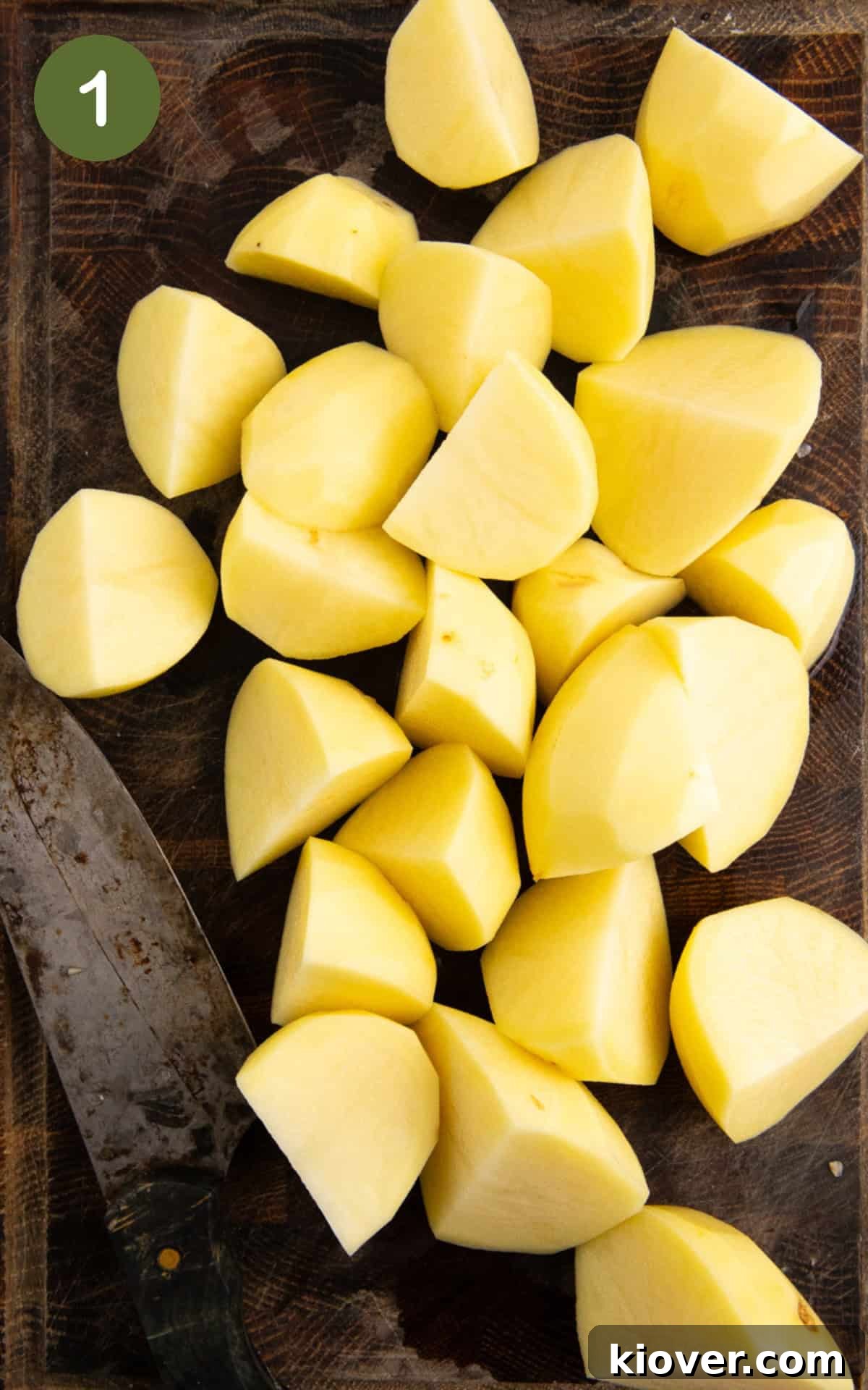 peeled and chopped white potatoes on a wooden chopping board.