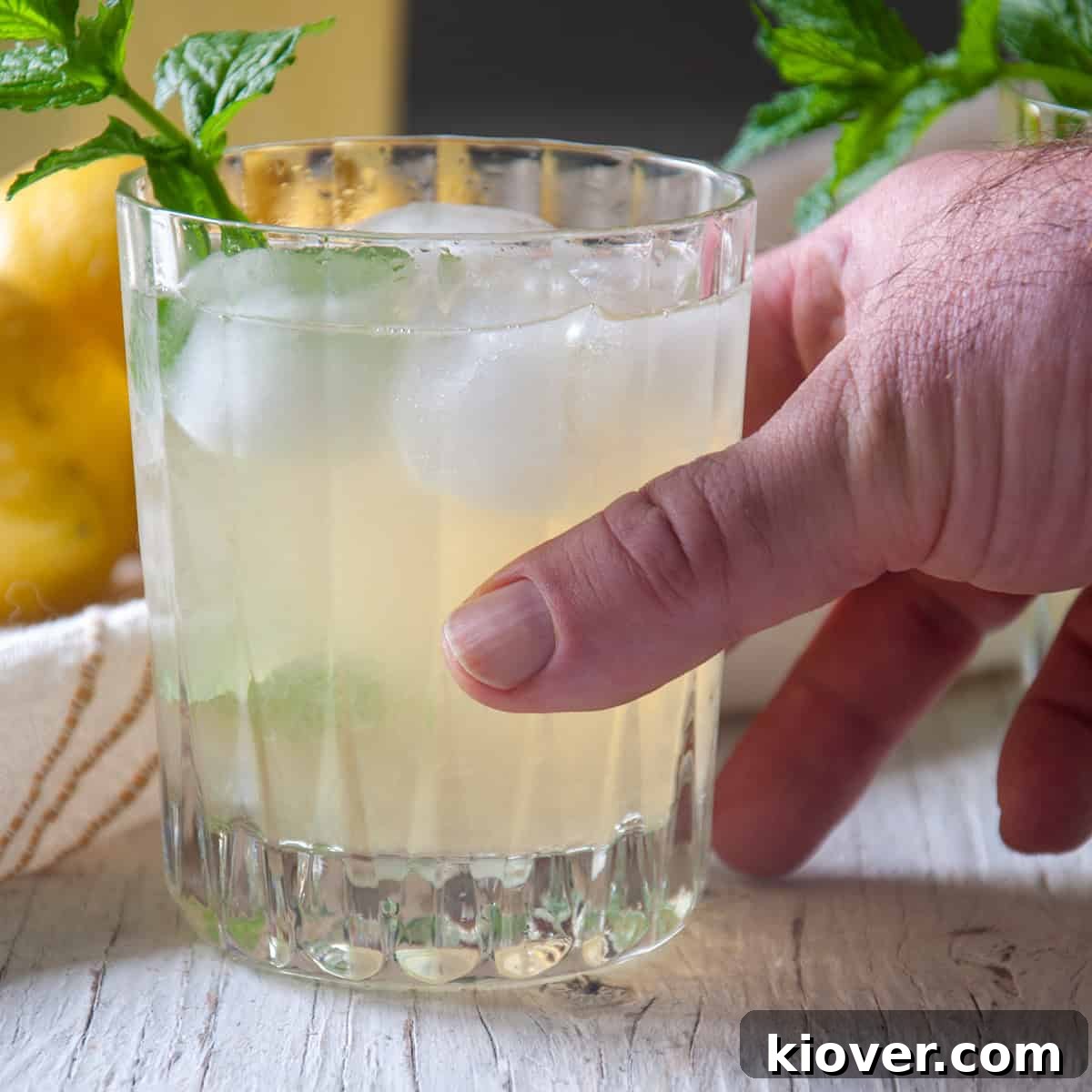 Honey Lemonade A glass of honey lemonade with a hand picking it up.
