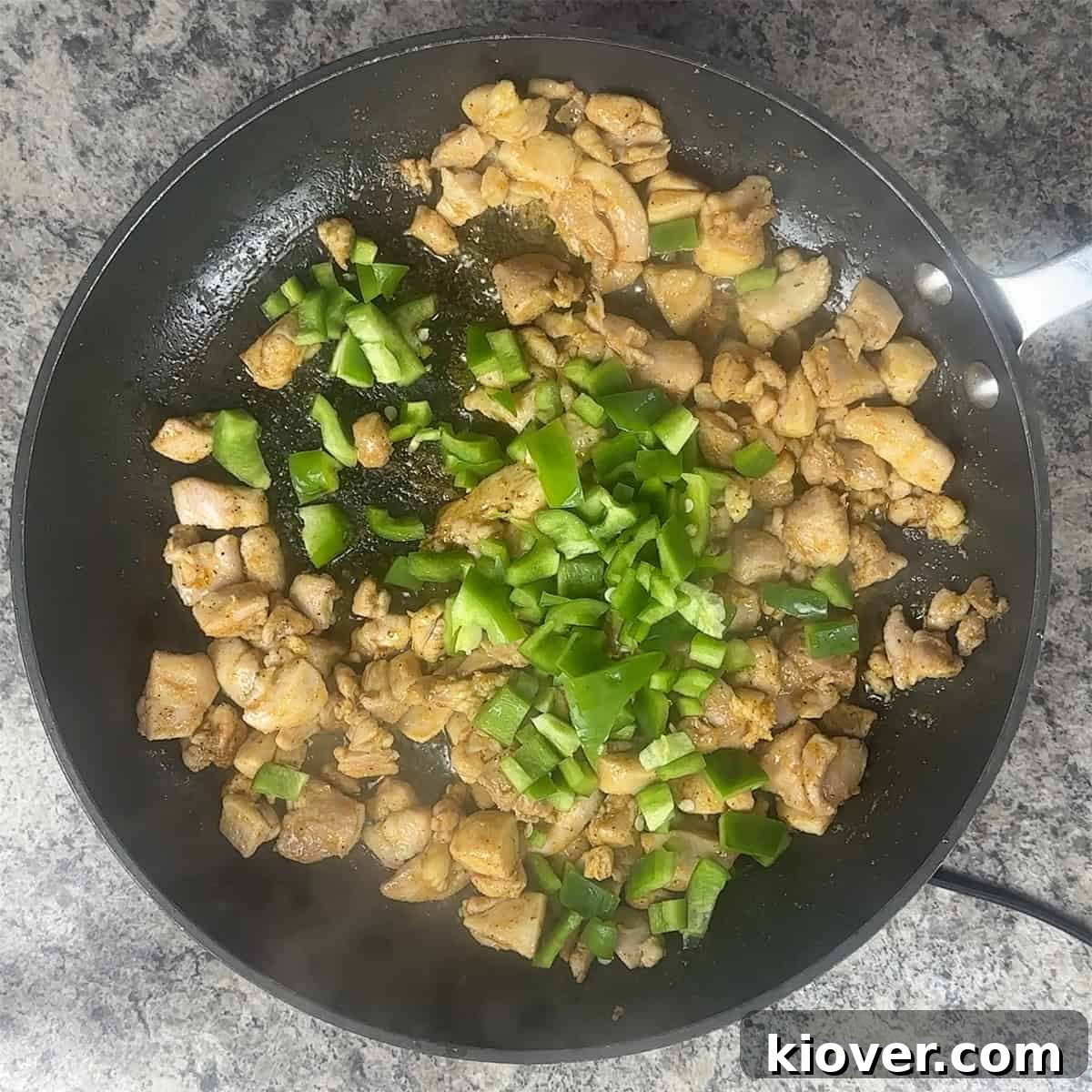 Chicken thigh and green bell pepper in a skillet.