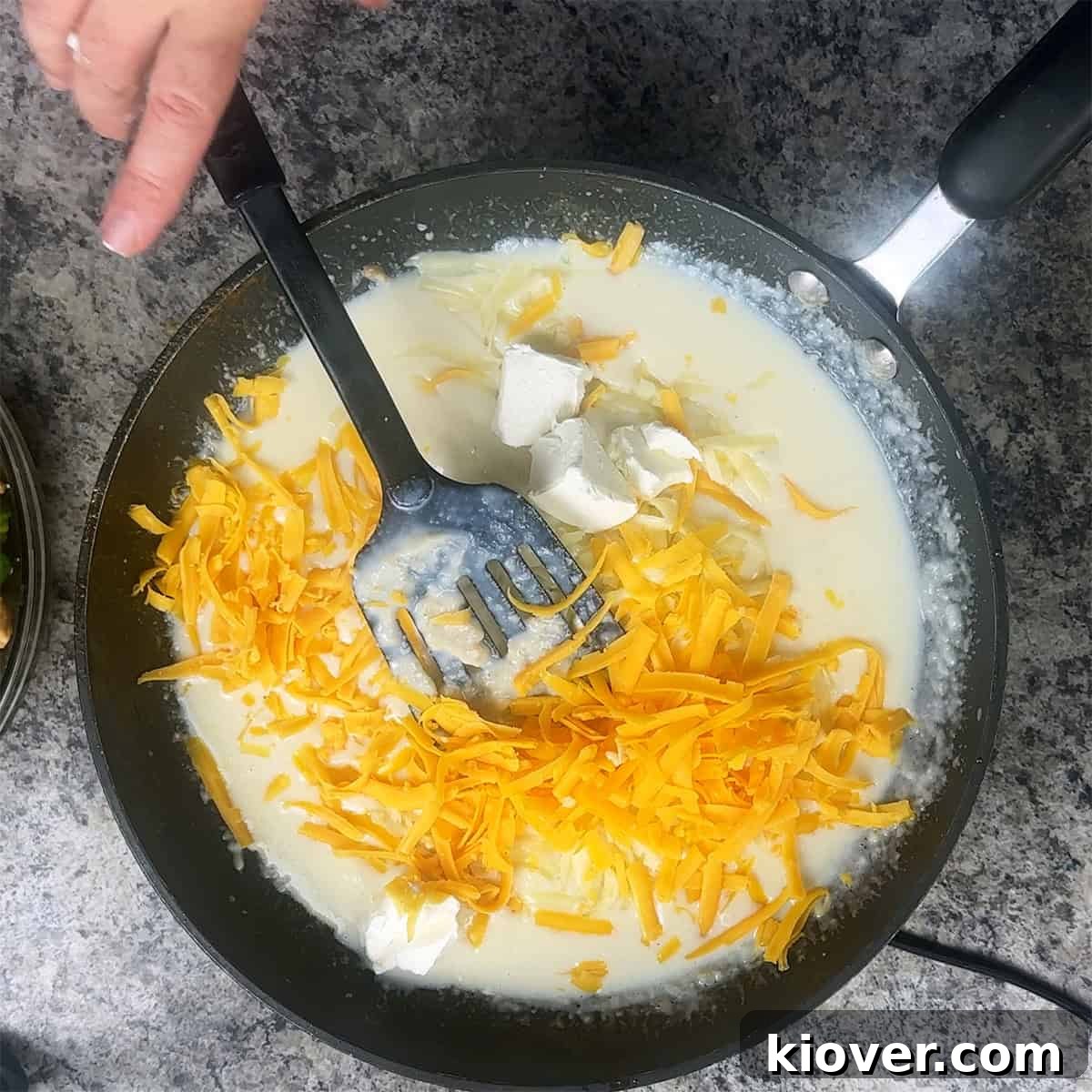 Cheddar cheese and cream cheese mixing into bechamel sauce.