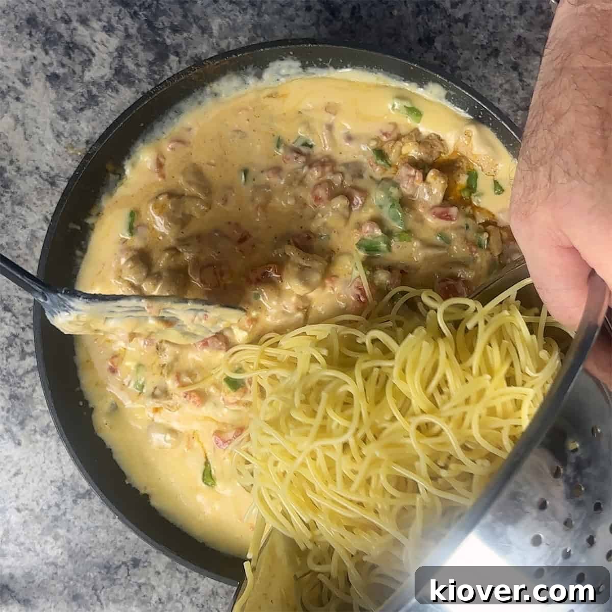 Dumping spaghetti into cheese mixture.