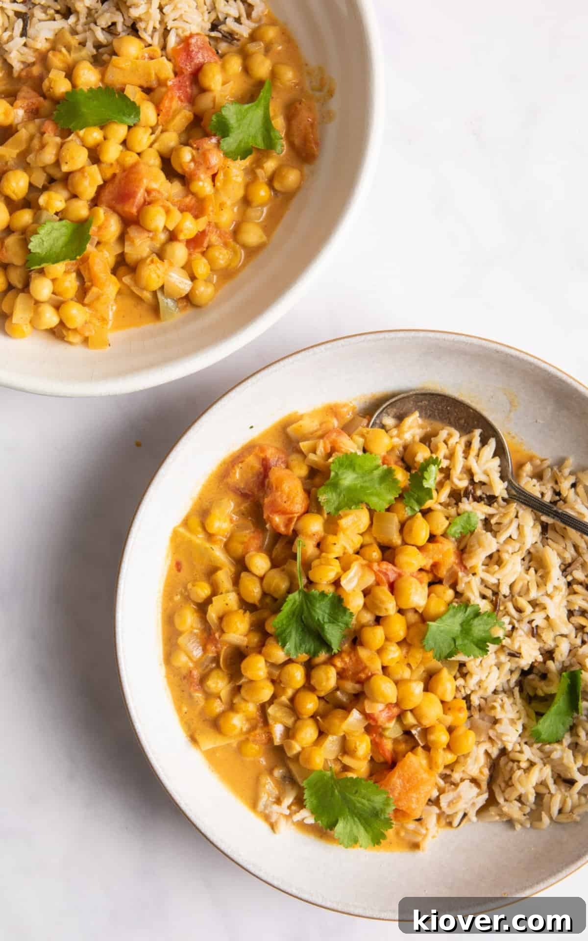 Hearty Slow Cooker Chickpea Curry 6 Two white bowls of chickpea curry with rice.