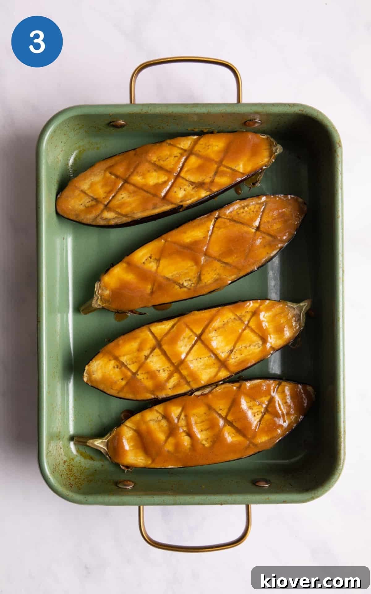 Perfectly Sweet and Savory Miso Glazed Aubergine Nasu Dengaku 6 Aubergine halves, already softened and scored, sitting in a green baking tray, generously coated with the rich miso marinade, ready for their second round of baking.