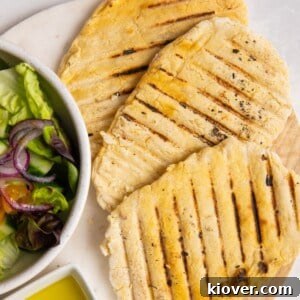 Three golden-brown gluten-free flatbreads arranged on a pristine white plate, garnished with fresh herbs and a drizzle of olive oil.