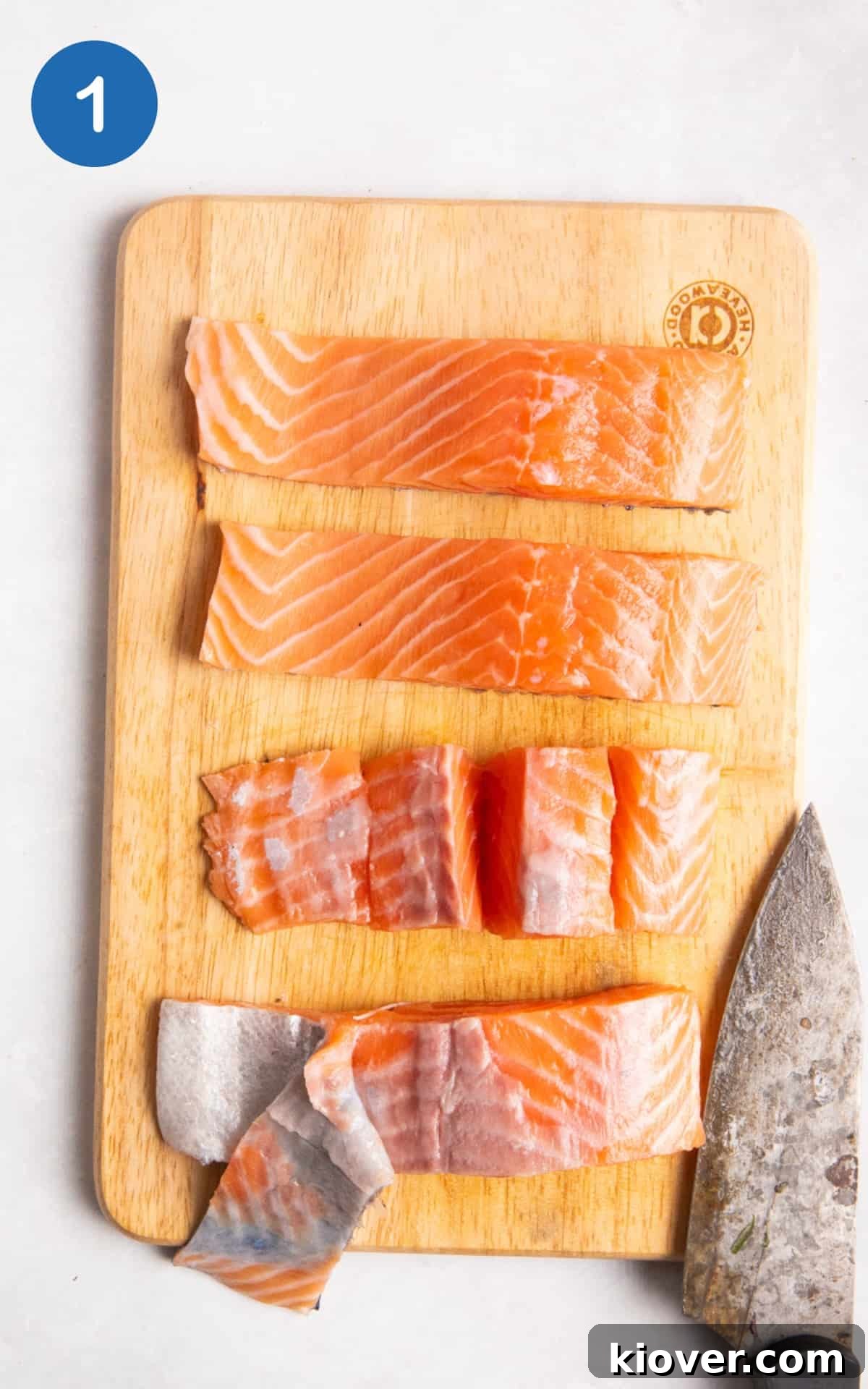 Fresh salmon fillets being expertly chopped into uniform cubes on a wooden cutting board.