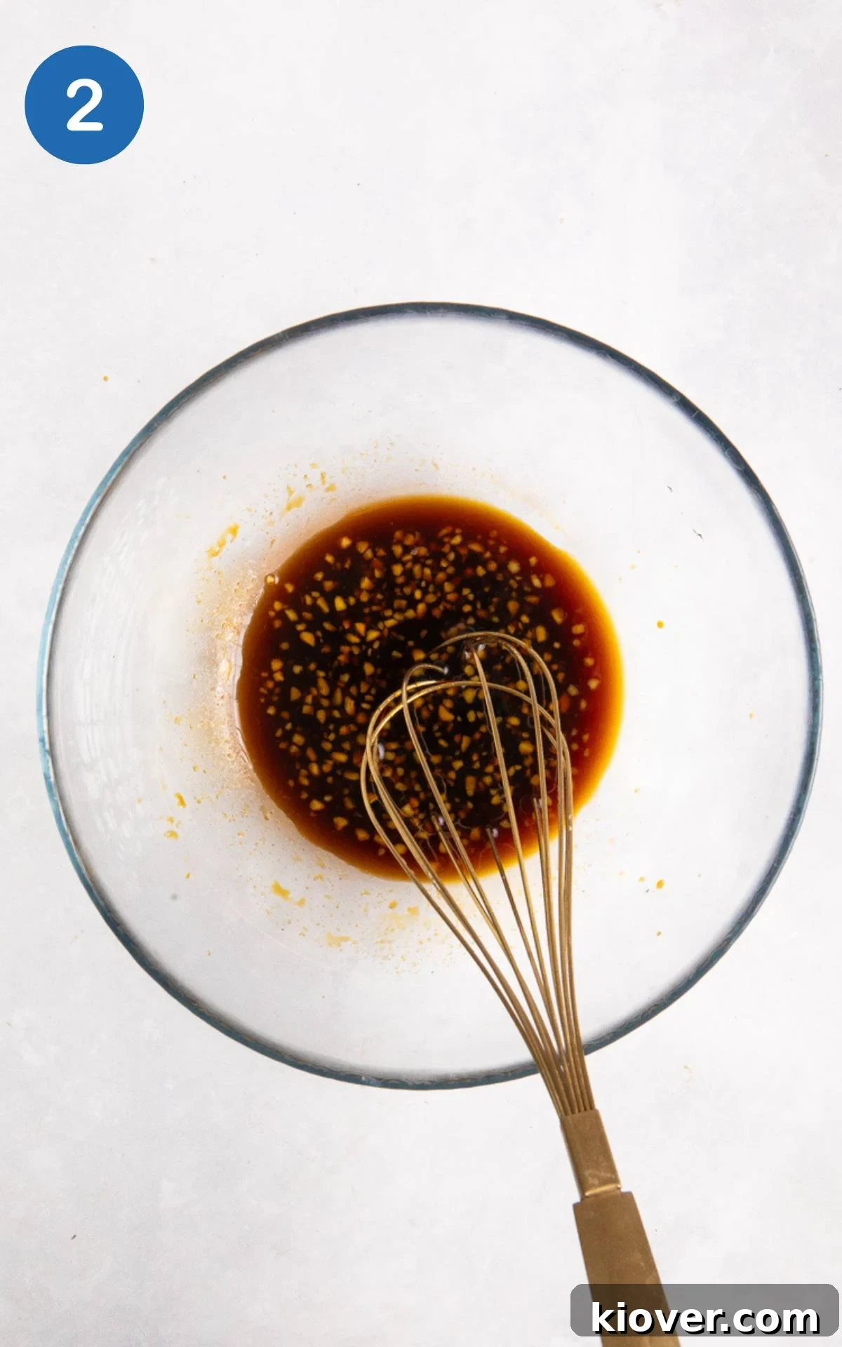 A rich, brown Asian-inspired marinade for salmon skewers being mixed in a clear glass bowl.