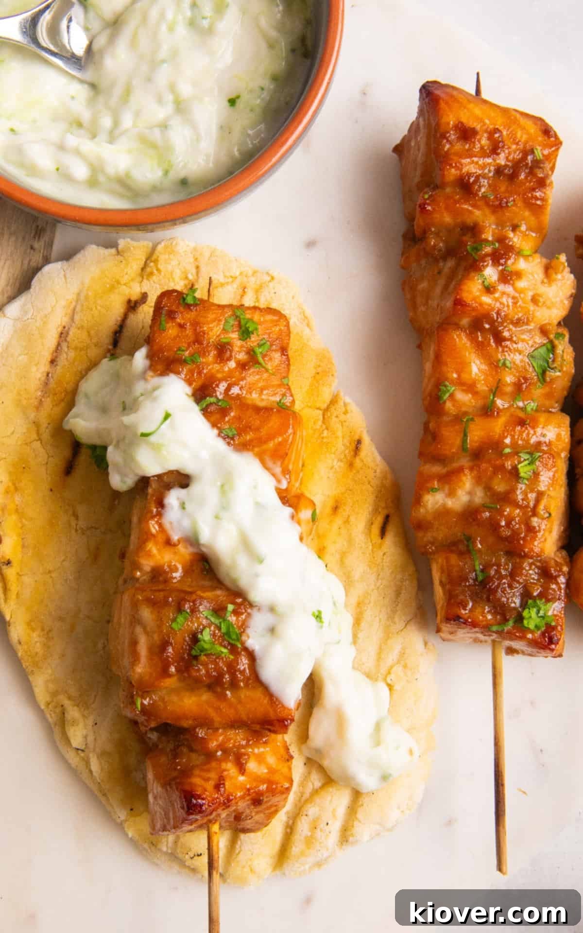 Close-up of perfectly cooked Asian Salmon Skewers, garnished with a creamy white sauce.