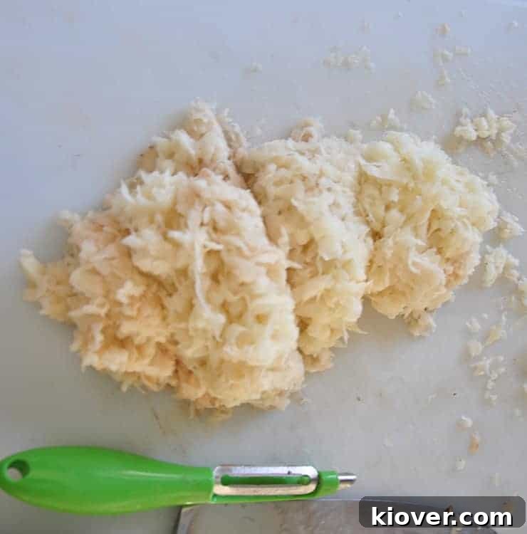 Finely shredded potatoes resting on a cutting board, ready for the next step in making tater tots.