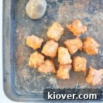 tater tot recipe feature image. Tater tots on a pan with a potato