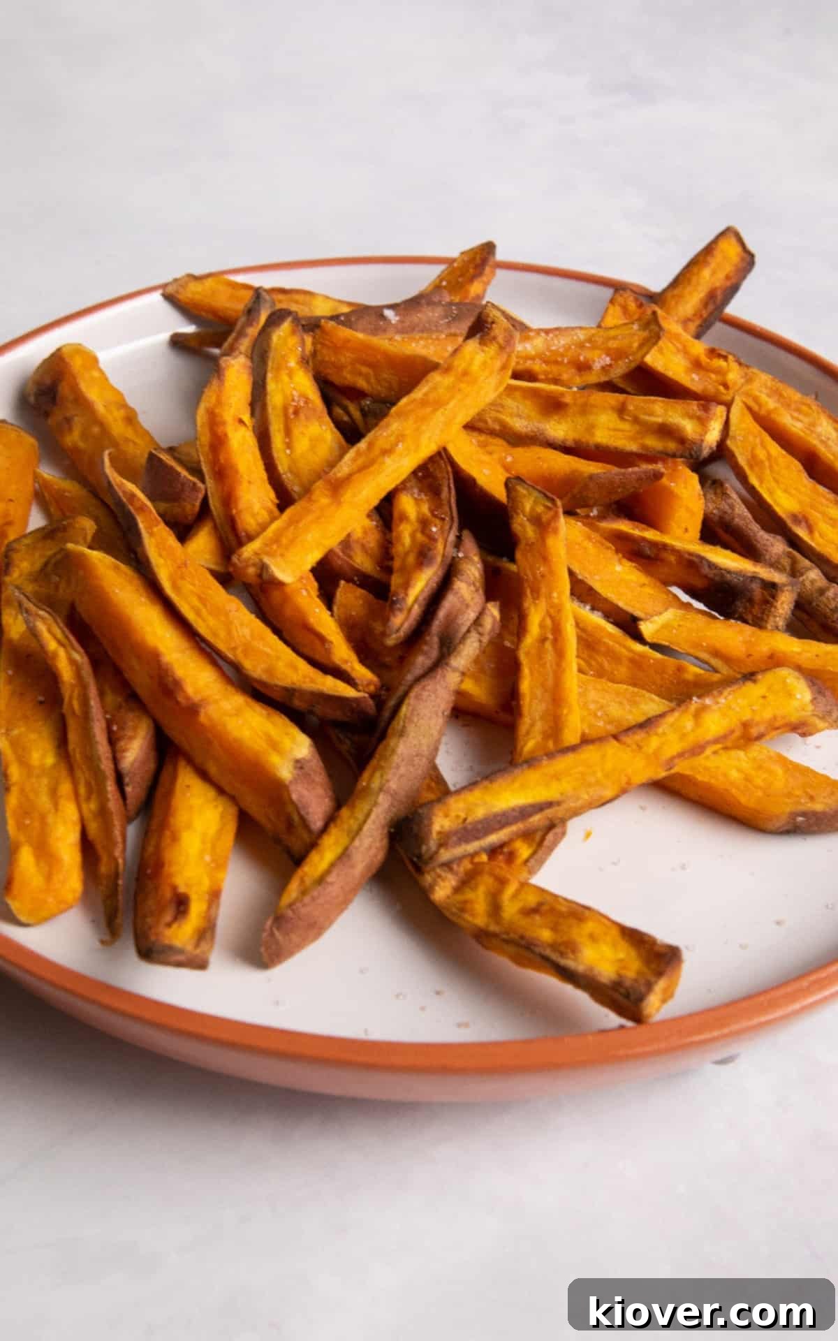 Sweet potato fries on white plate with orange rim.