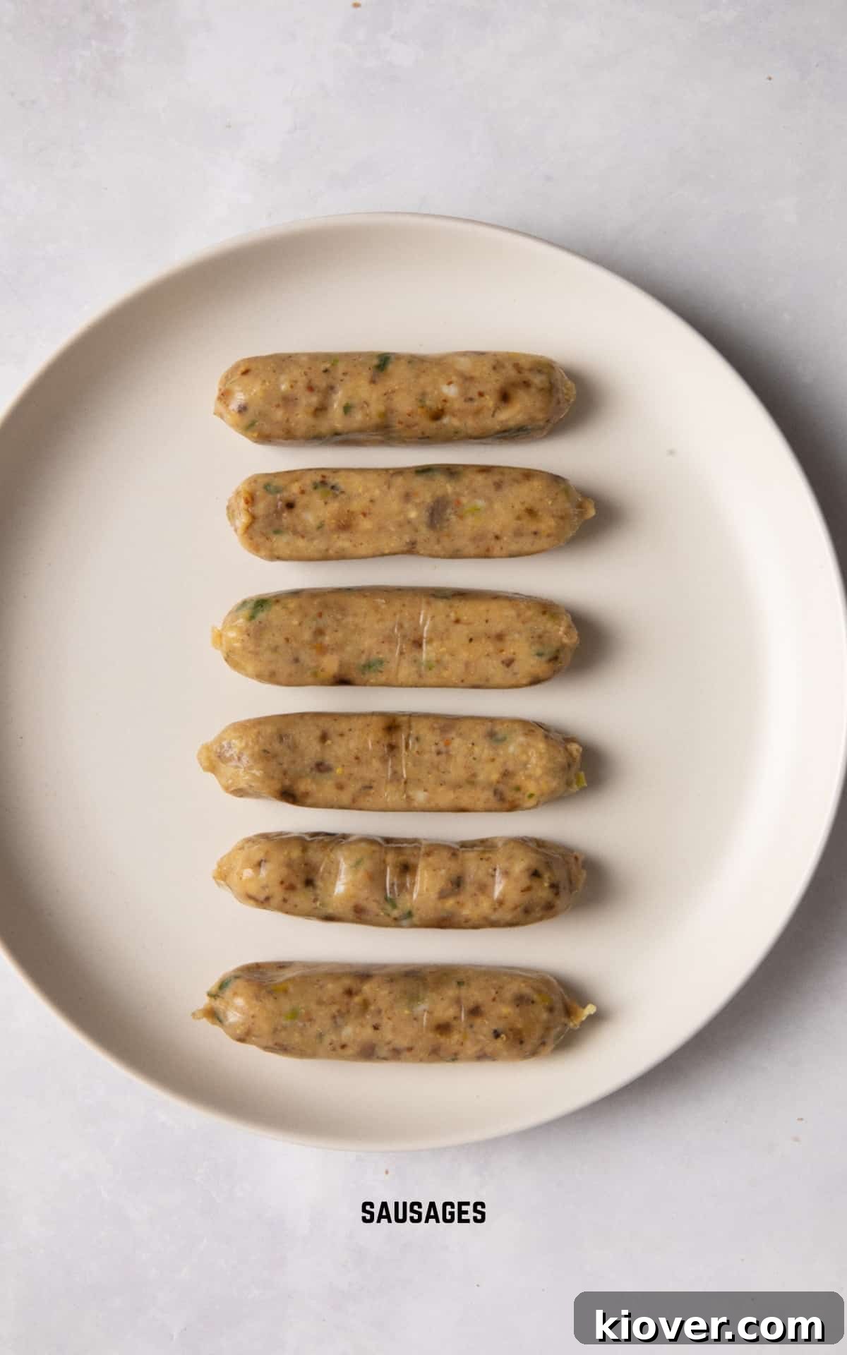 A selection of sausages laid out on a clean white plate, ready for air frying.
