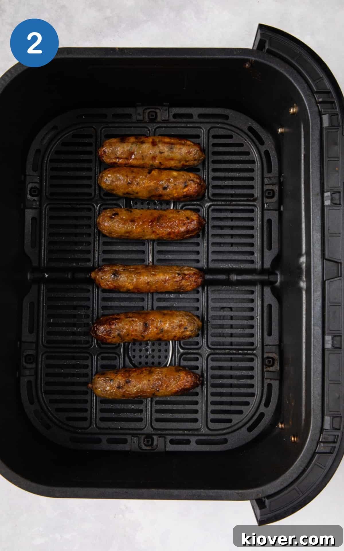 Perfectly cooked, golden-brown sausages resting in the black air fryer basket after cooking.