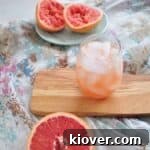 greyhound cocktail recipe on wood platform with grapefruits