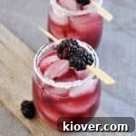 A blackberry black dog cocktail on a wood plank