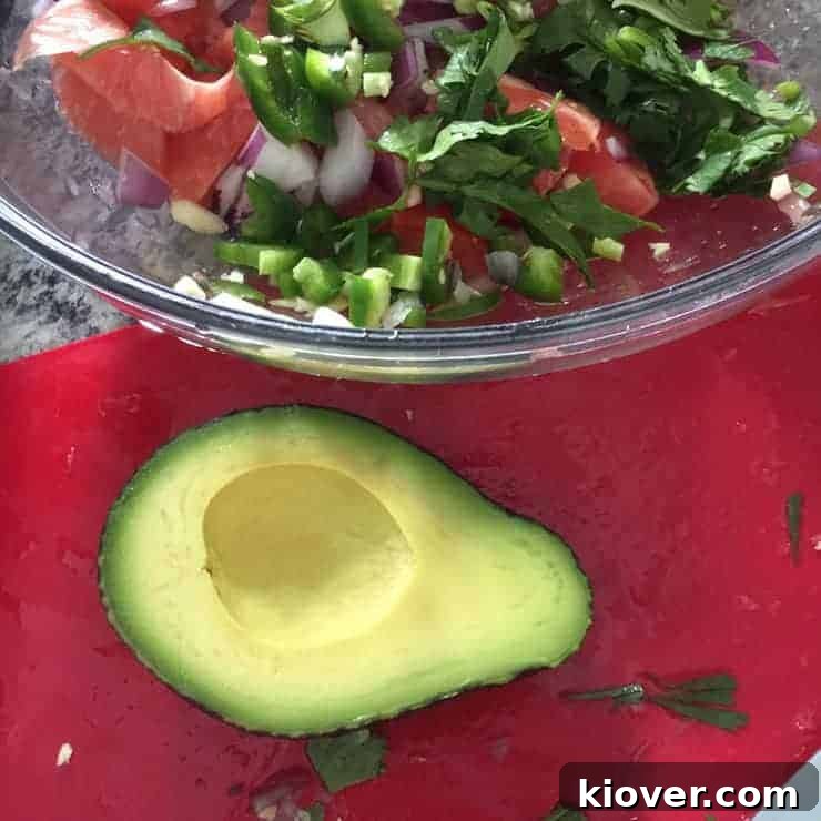 Beautifully ripe avocado ready for ceviche preparation, with other mixed ingredients in the background