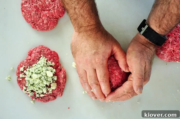 Enclosing two quarter pound patties around a bit of blue cheese for this hamburger.