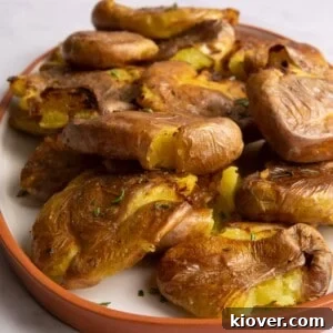 close up of smashed potatoes on white plate with orange edge.