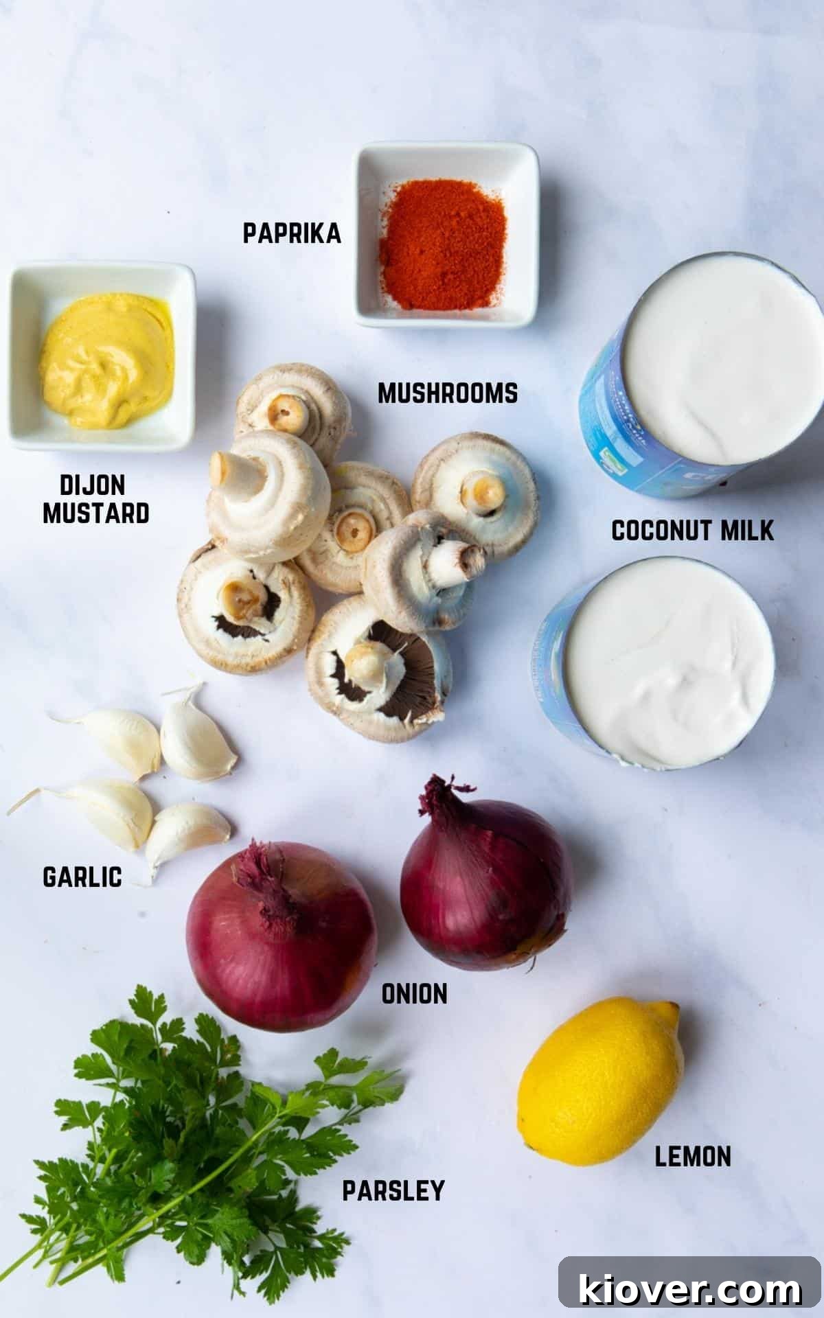 All the fresh ingredients required to make One-Pot-Vegan Mushroom Stroganoff, neatly laid out on a pristine white marble background, showcasing their vibrant colors and freshness.
