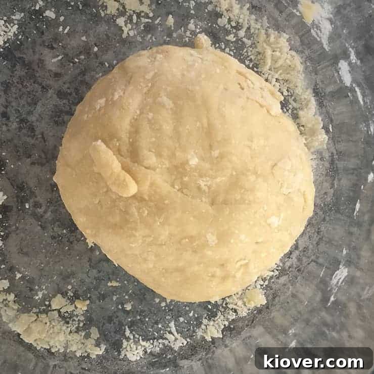 A perfectly smooth and elastic ball of noodle dough rests on a sleek granite countertop, ready for the next stage of preparation.
