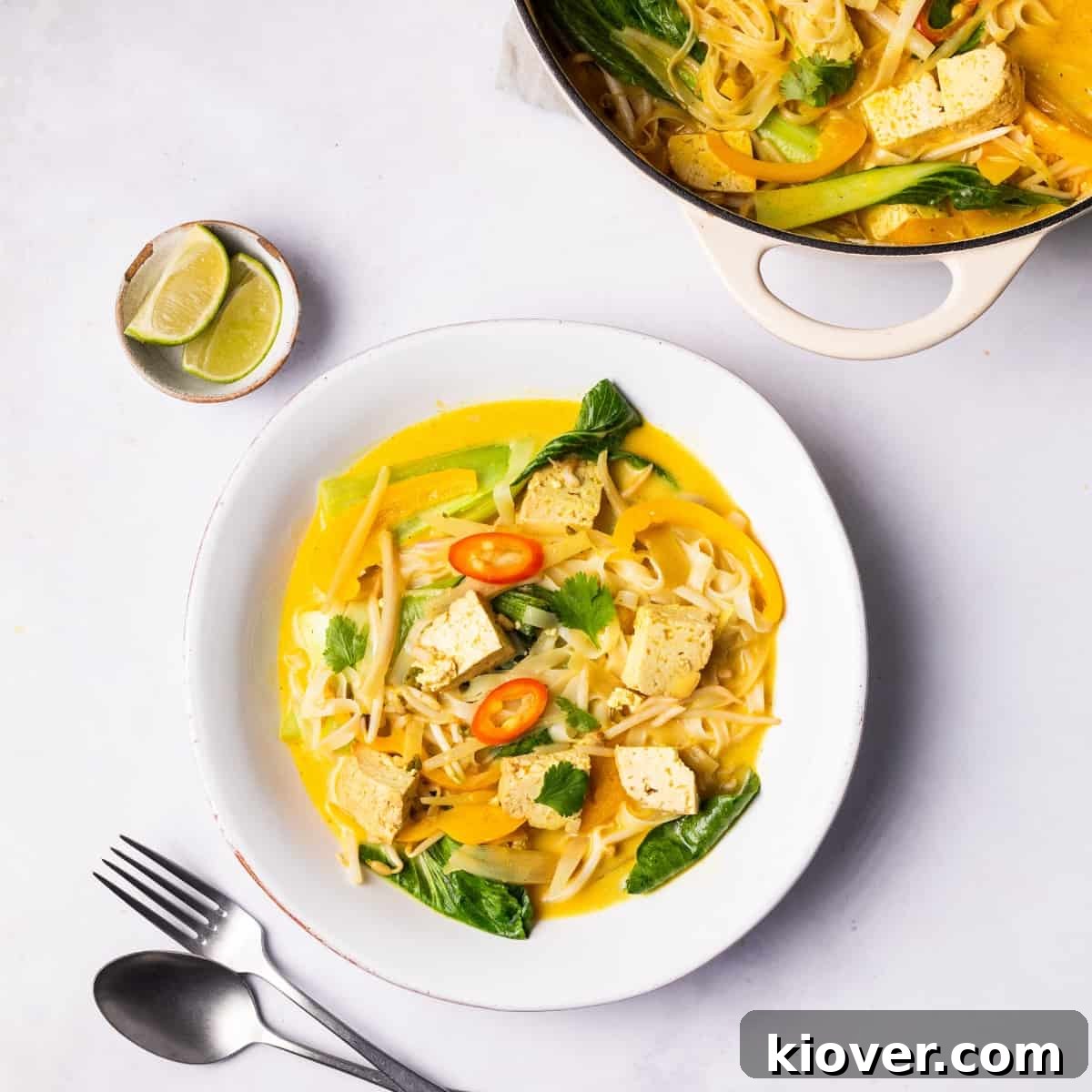 A vibrant bowl of Vegan Laksa garnished with fresh herbs and chili, showcasing its rich, creamy texture and colorful ingredients.