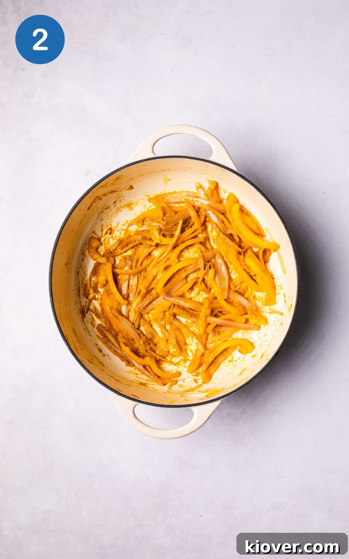 Shallot, bell pepper, and laksa paste sizzling in a large pot on the stovetop, releasing aromatic steam and developing deep flavors.