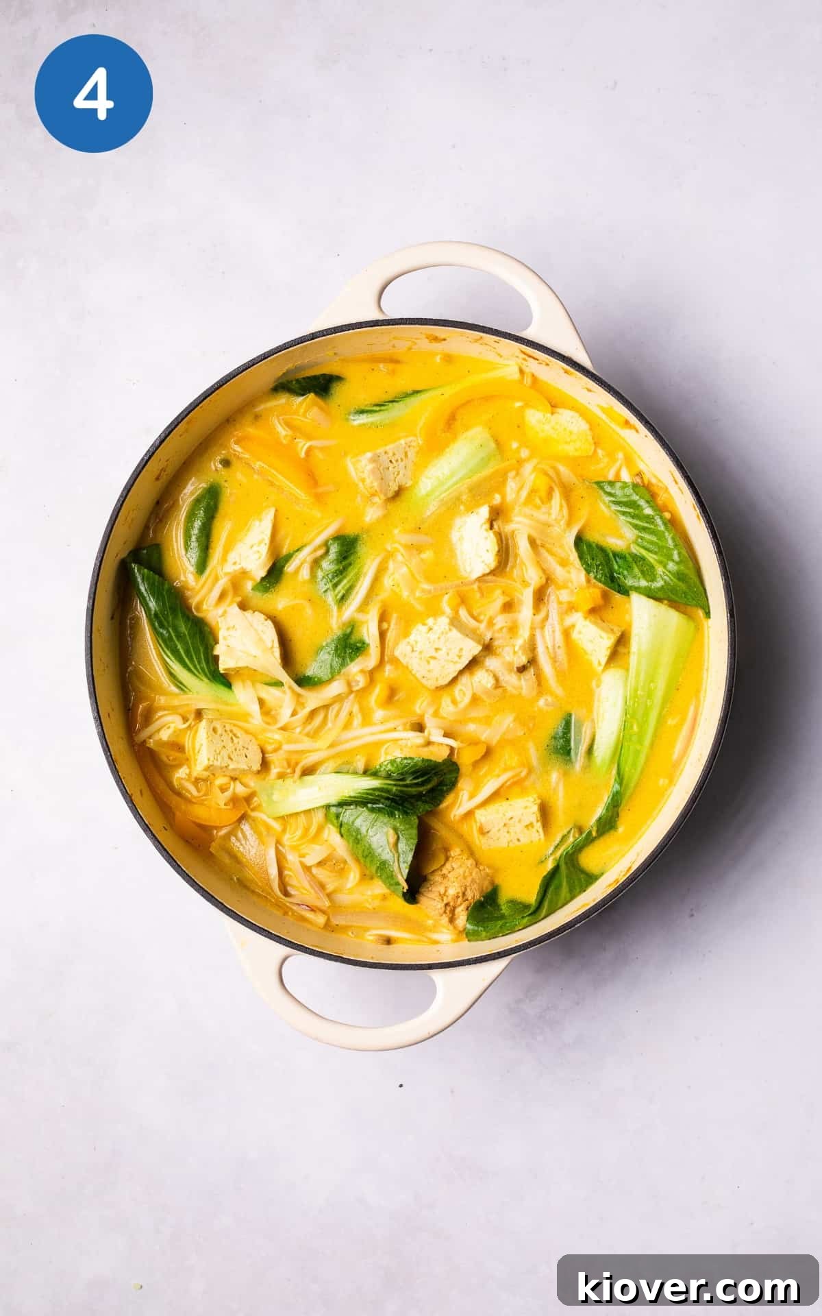 Vegan laksa simmering in a pot with coconut milk, vegetable stock, bean sprouts, pak choi leaves, and rice noodles, cooking to perfection in a creamy broth.