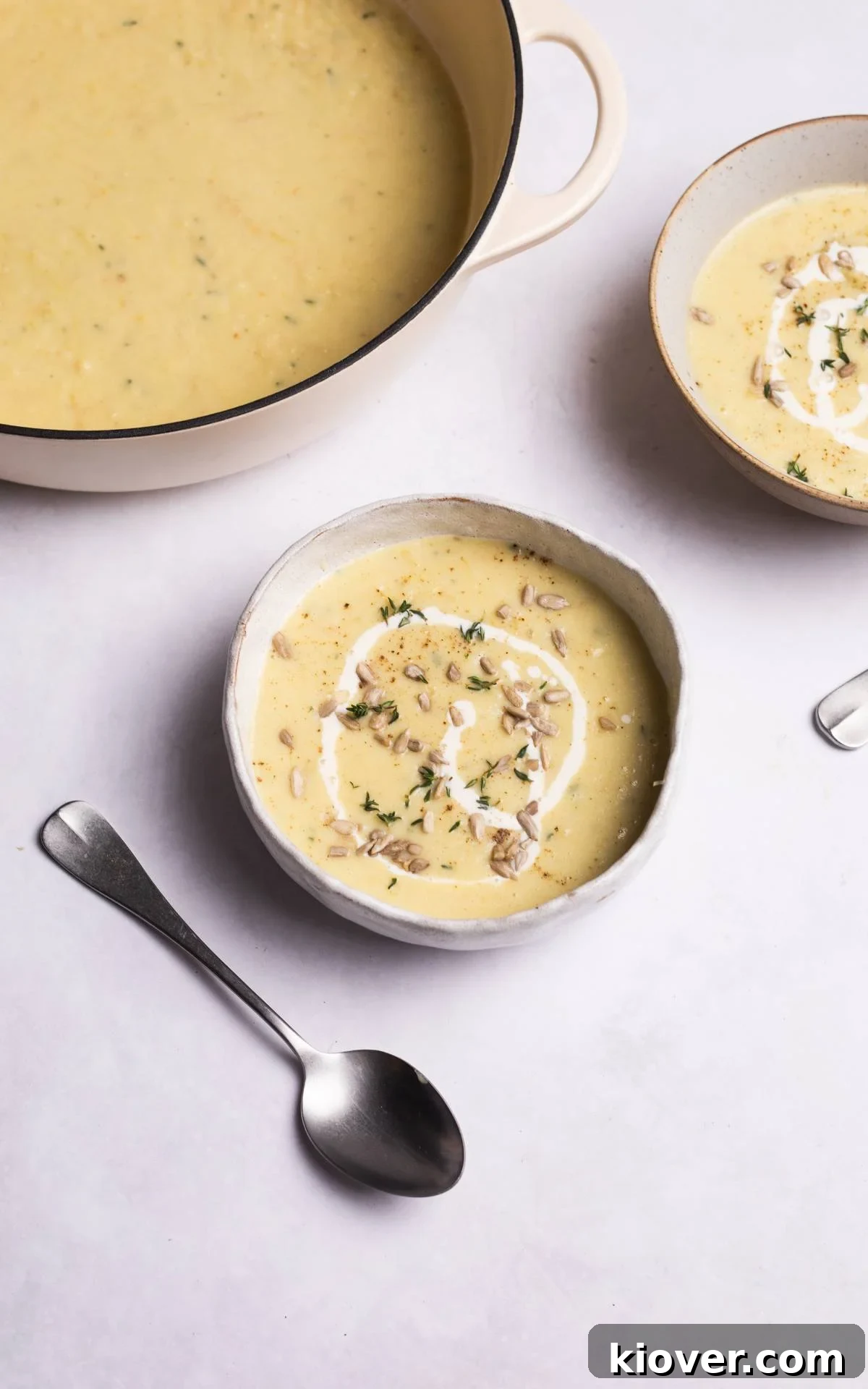A bowl of creamy parsnip soup, elegantly garnished with toasted sunflower seeds and a sprinkle of black pepper, ready to be enjoyed.