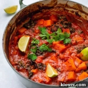 sweet potato and chickpea curry served in a large green pot, garnished with fresh herbs.