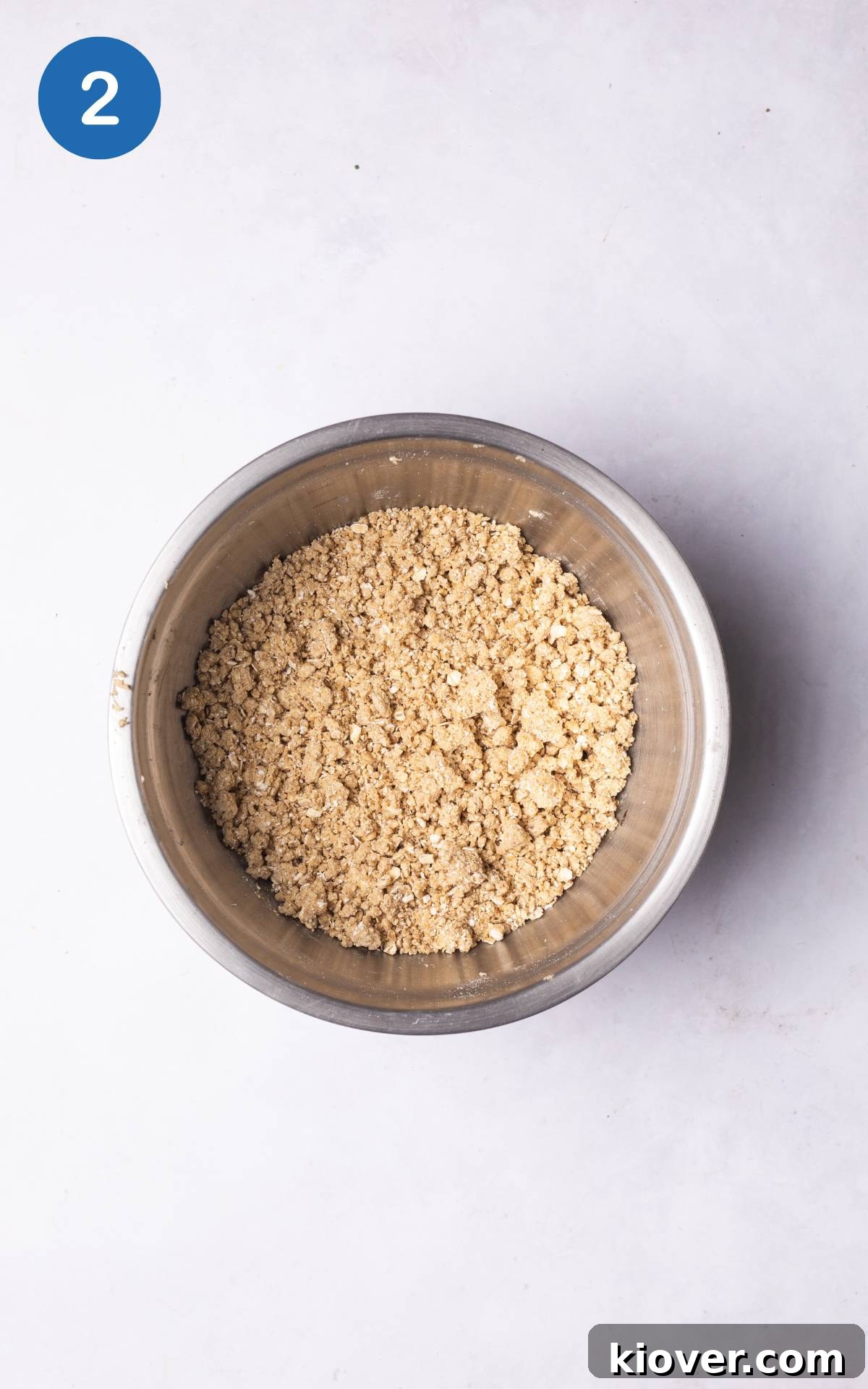 Close-up of a rustic oat crumble topping mixture, showing the distinct texture of oats, butter, and sweetener combined.